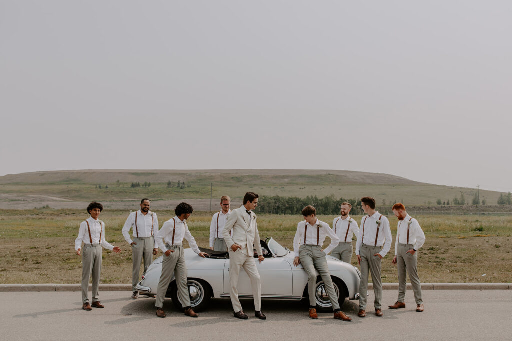 Groomsmen gathered around a vintage car at destination wedding 
